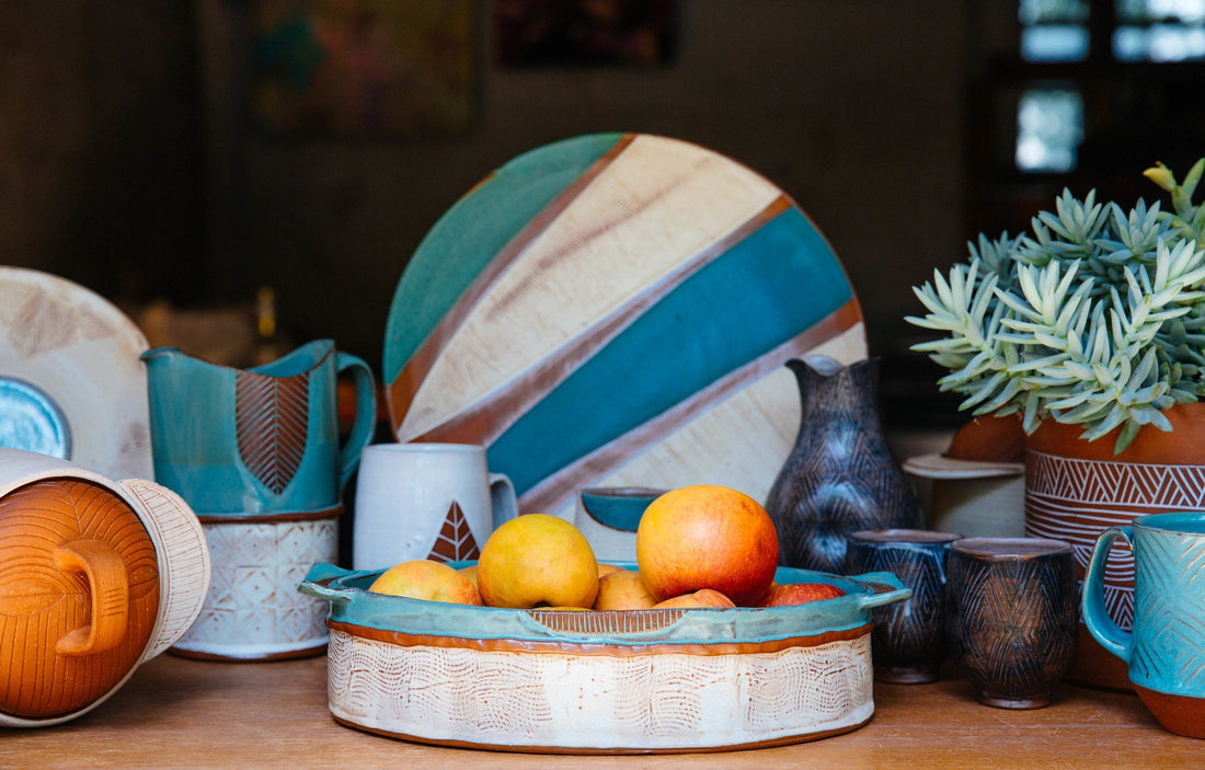 An assortment of blue, white and terracotta pottery on a wooden table. The pottery is made by Osa Atoe.
