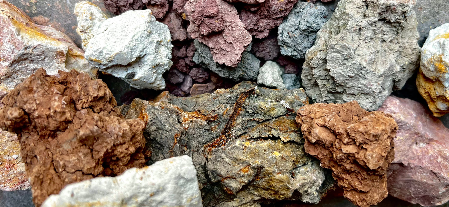 Various multicolored samples of clay clustered together. There are brown, white, gray purple and pink clays shown.